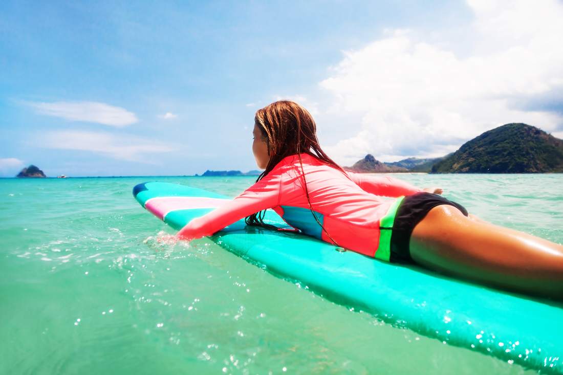 Girl padding out on surfboard